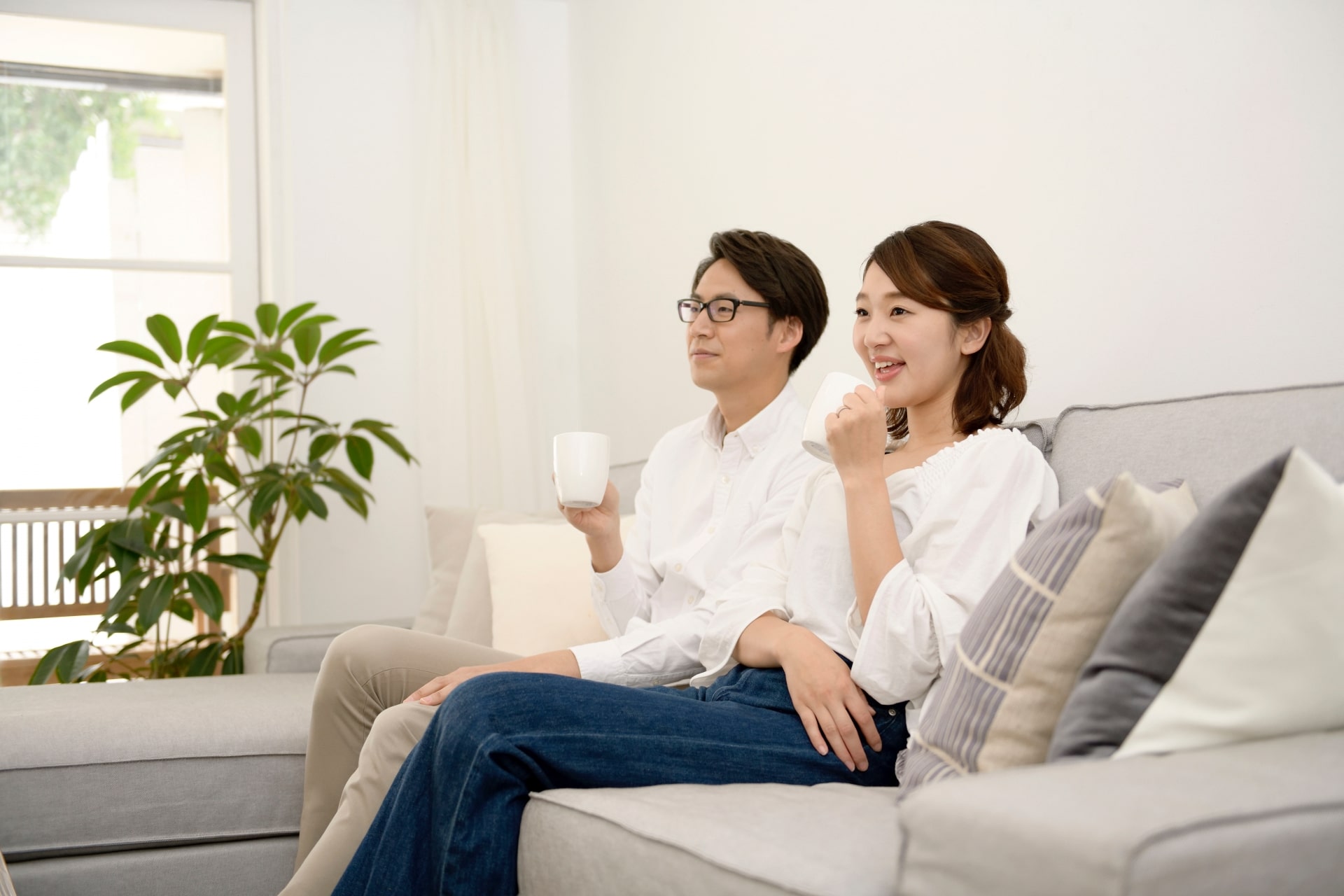Japanese couple at home watching TV and happy sipping coffee